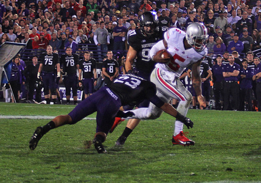 Junior quarterback, Braxton Miller (5), attempts to run through a tackle by Northwestern defender during a game Oct. 5 at Ryan Field. OSU won, 40-30.  Credit: Shelby Lum / Photo editor