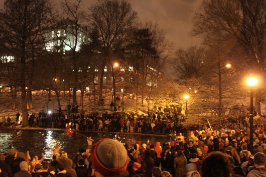 Fans stand around Mirror Lake while some jump in despite university efforts to control the event.  Credit: Ryan Robey / For The Lantern