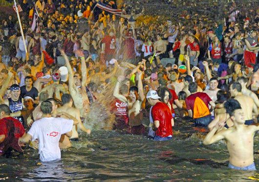 Ohio State fans jump in Mirror Lake as part of a Beat Michigan Week tradition in 2012. For this year’s jump, participants will be required to obtain a wristband in advance and file through a single entry point in order to reach the lake.<br />Credit: Daniel Chi / For The Lantern