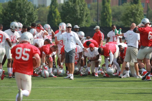 Members of the OSU football team huddle around coach Urban Meyer during the first day of fall practice Aug. 4 at the Woody Hayes Athletic Center in Columbus. Credit: Tim Moody / Lantern sports editor