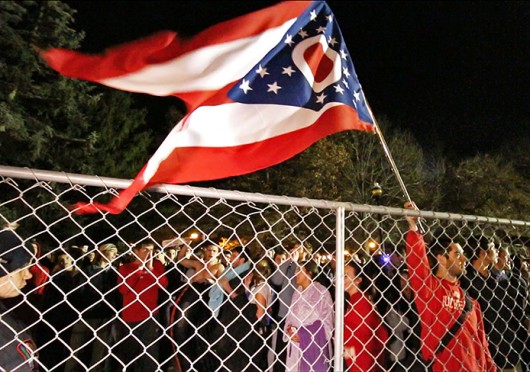  A man holds an Ohio flag over fences surrounding the Mirror Lake area on Nov. 24. Credit: Yann Schreiber / Lantern reporter 
