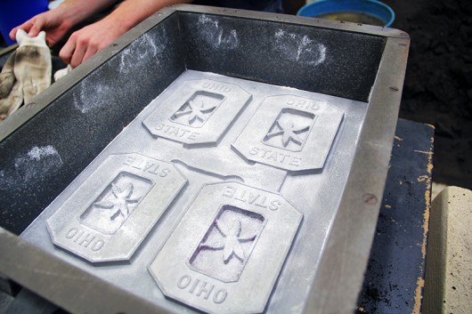 Students in the OSU Foundry Club prepare the Block O mold for pouring on Tuesday, Oct. 7 in Watts Hall by using talcum powder to prevent sticking. Credit: Ian Bailey / Lantern Reporter
