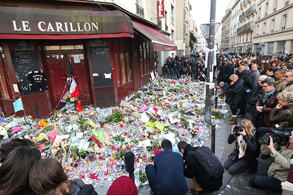 People lay flowers and candles in front of the Le Carillon restaurant, one of the first locations hit by Friday’s attacks, together with the Petit Cambodge restaurant, in Paris on Nov. 16. Credit: Yann Schreiber | For The Lantern 