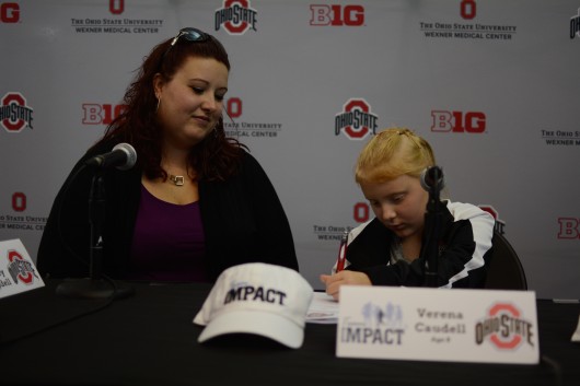 Verena (right) signs her official letter, signifying her spot on the OSU synchronized swimming team through Team IMPACT, while her mother, Ashley, looks on. Credit: Kevin Stankiewicz | Assistant Sports Editor 