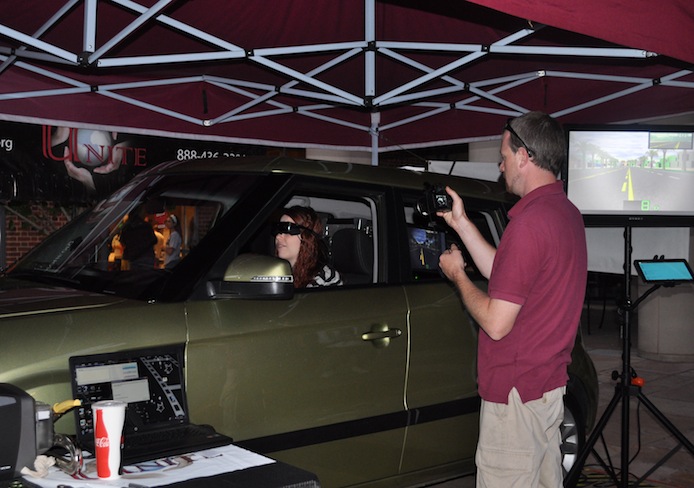 Marty Burke, a driving instructor with the Arrive Alive program, takes a photo of Megan Swanger, a third-year in nursing, while she does the Distracted Driving Simulator Sept. 26 outside of Ohio Union. Credit: Liz Young / Campus editor